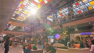 Im Inneren des Shopping-Centers ist eine bunte Glaskuppel zu sehen, durch die Sonnenlicht scheint.