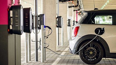 Ein E-Auto steht auf einem Parkplatz und ist an einer Ladestation angeschlossen