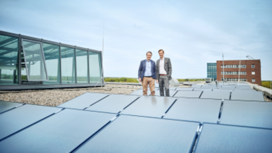 Zwei Männer stehen auf einem Dach mit Solaranlagen.