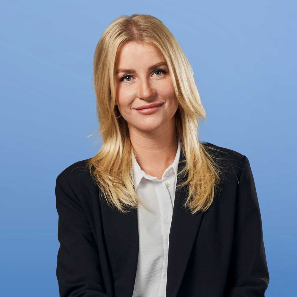 Auf dem Bild ist das Portrait einer jungen Frau zu sehen, vor einem blauem Hintergrund